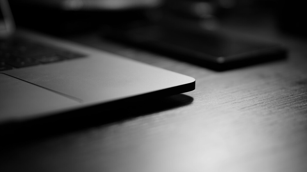 Mesa de redação com documentos financeiros, laptop e apontamentos de investigação